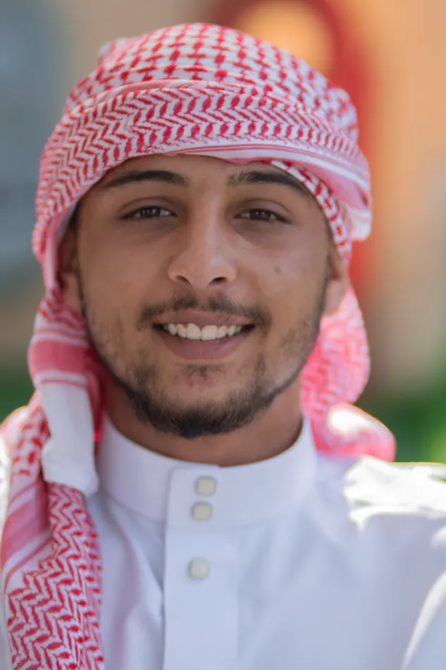 صورة قريبة لشخص يرتدي غطاء رأس أحمر وأبيض، مع عزل الخلفية للتركيز على الوجه